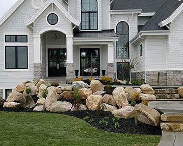 Rock landscaping with mulch and flowers in front of house