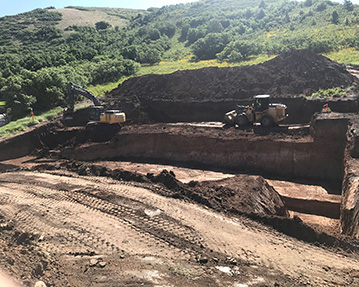 Excavator and front end loader digging a large basement