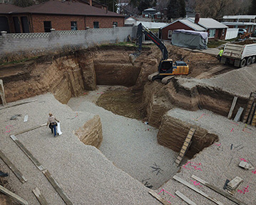 Excavator backfilling basement with gravel