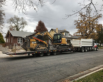 Dump truck pulling a mini excavator and skid steer on a pup trailer