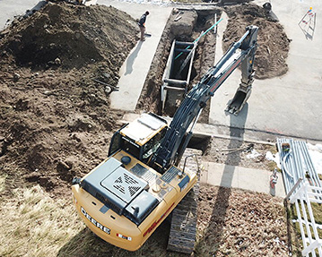 Aerial picture of excavator putting pipe into a trench