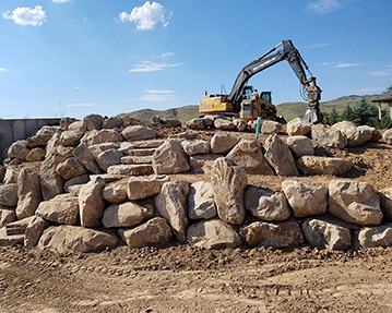 Rock walls and stairs with excavator and skid steer in background